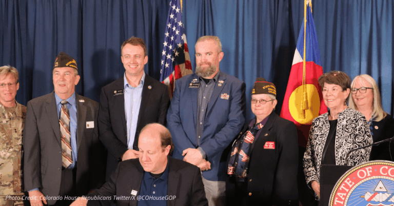 Ryan Armagost at bill signing to protect veterans, standing with lawmakers and veterans under Colorado and U.S. flags