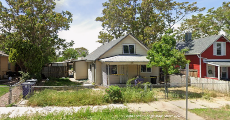 Abandoned Denver home with overgrown yard and boarded windows awaiting city cleanup