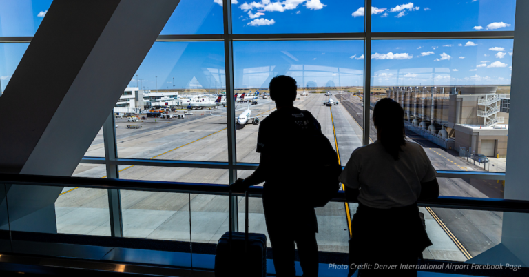 Silhouetted travelers look out over runways at Denver International Airport
