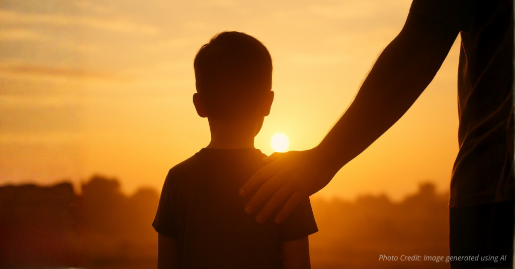 Parent’s hand on child’s shoulder at sunrise symbolizing protection