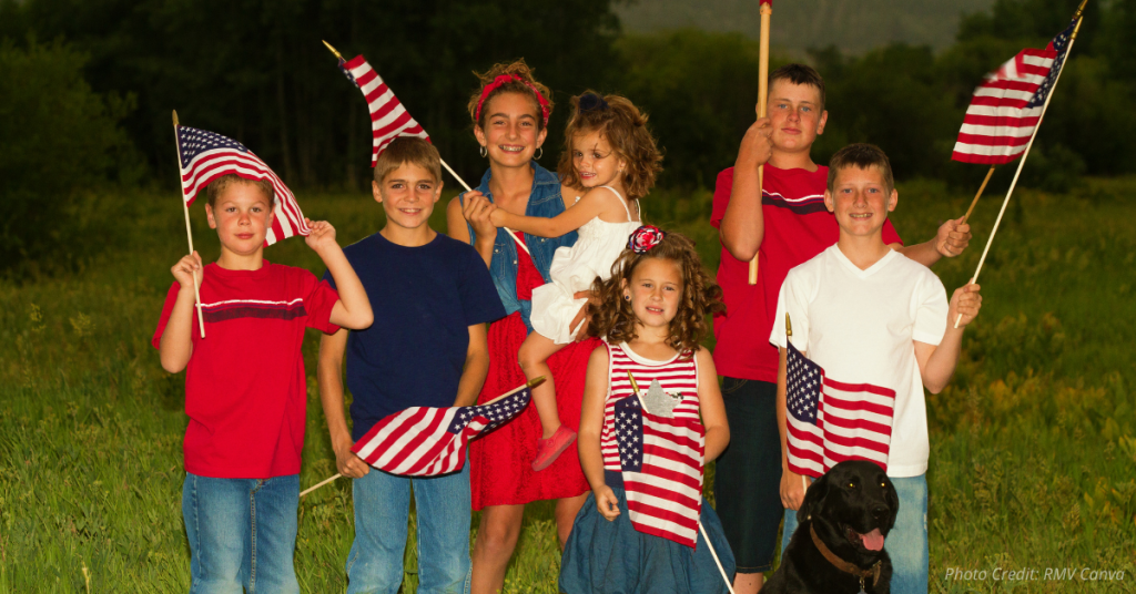Group of patriotic children holding American flags outdoors at sunset