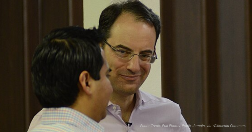 Phil Weiser speaking with two men at an event in 2018