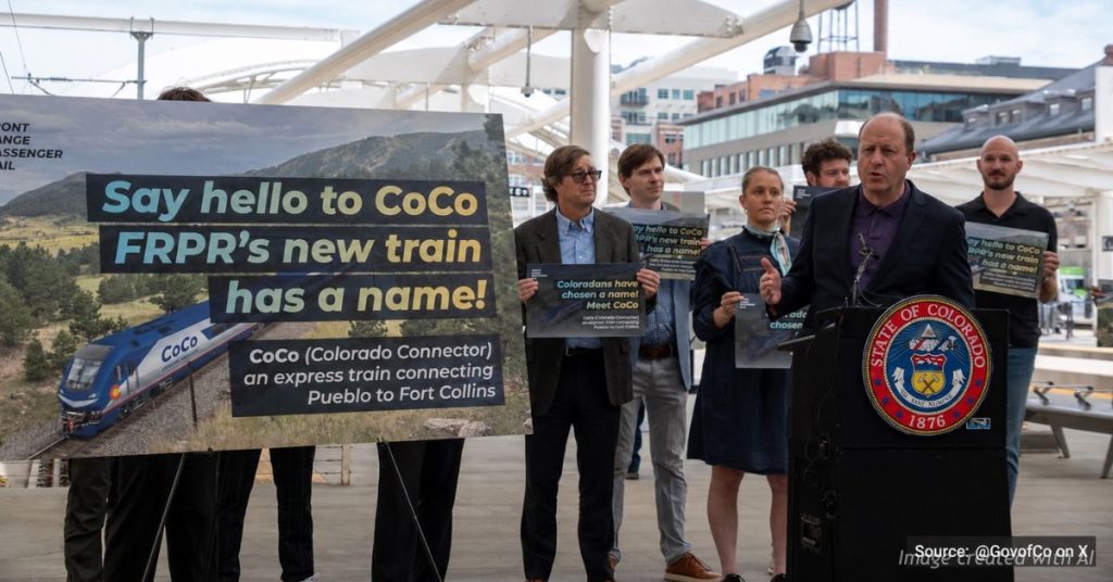 Governor Jared Polis speaks at a podium during the Colorado Connector name reveal as state and FRPR staff stand behind him holding branded signs reading "Say hello to CoCo, FRPR's new train has a name."