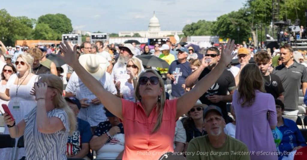Woman raises hands in prayer at Rededicate 250 gathering near the U.S. Capitol