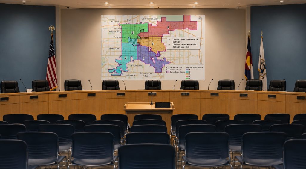 Denver Public Schools board chamber with the challenged school board district map displayed behind the dais.