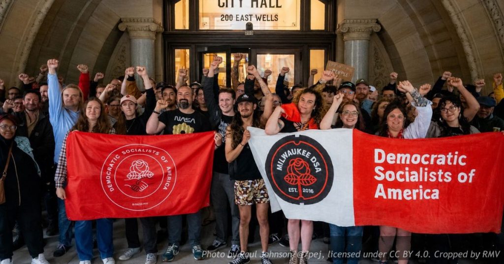 Democratic Socialists of America members raise their fists and hold DSA banners outside Milwaukee City Hall.