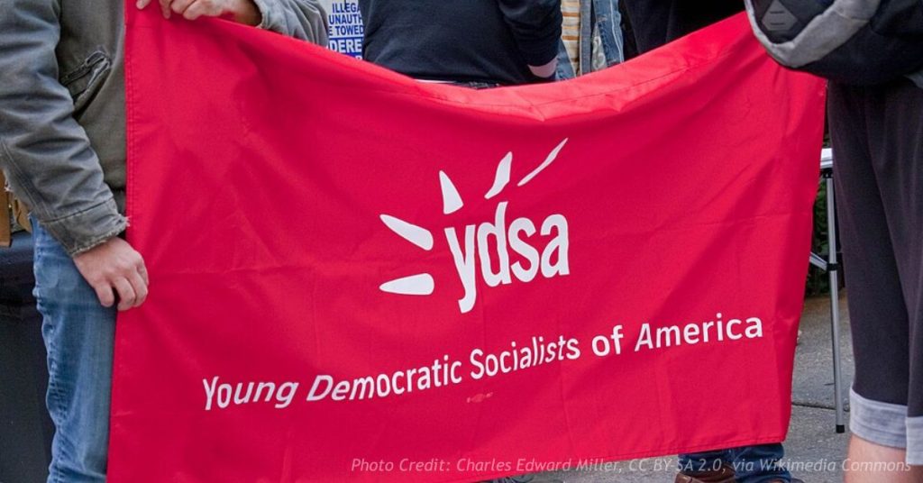 A red banner reading "ydsa — Young Democratic Socialists of America" held open by several people on a sidewalk.