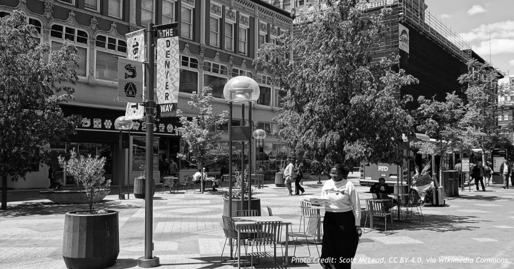 Pedestrians and shade trees along Denver's 16th Street Mall, lined by downtown high-rise buildings