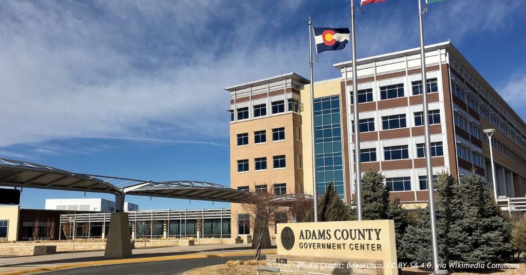 Adams County Government Center building with U.S., Colorado and county flags flying at the entrance sign