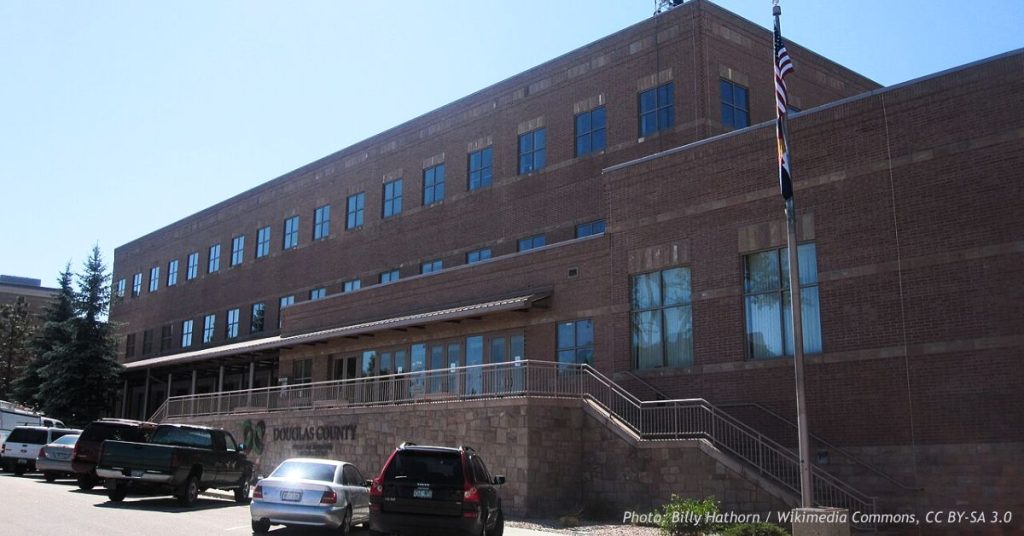 Douglas County government building in Castle Rock, Colorado, with U.S. and state flags outside the entrance.