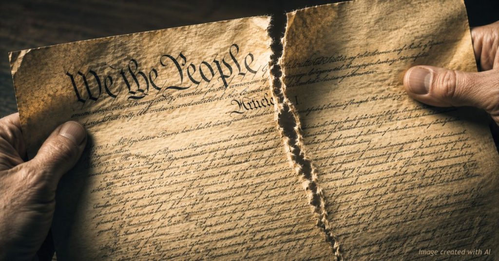 Aged parchment copy of the U.S. Constitution, with "We the People" visible at the top, being torn in half by two hands.