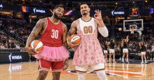 Satirical image of two male basketball players in a packed WNBA arena wearing a pink tutu and floral sundress as women players warm up near the basket.