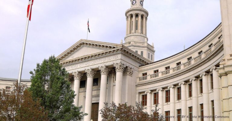 The Denver City and County Building, a neoclassical civic building with a columned portico and clock tower, under an overcast sky.