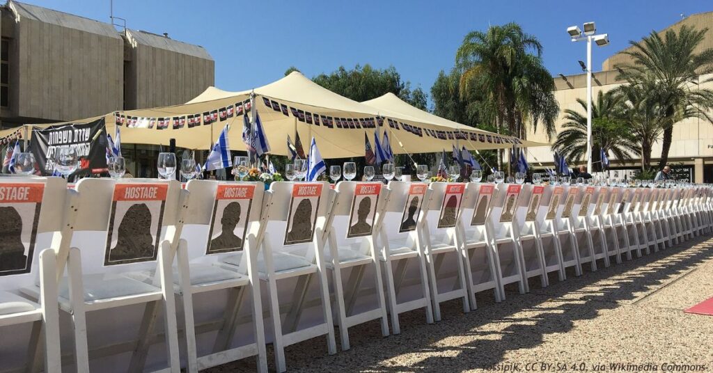 Rows of empty white chairs marked HOSTAGE line a long Shabbat table set for Israelis taken captive on October 7, 2023