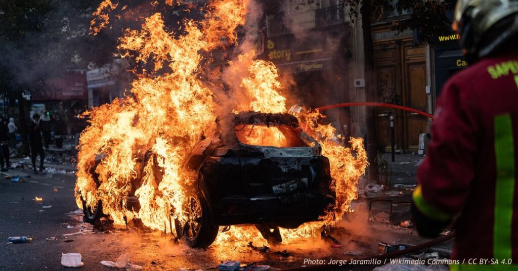 Paris firefighters extinguish a burning car outside a manga shop during riots and demonstrations on October 17, 2026.
