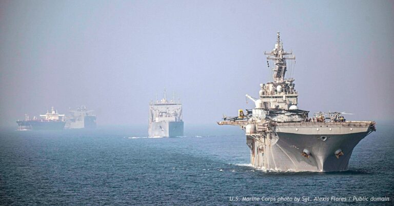 USS Essex leads a formation of U.S. military vessels through the Strait of Hormuz in September 2021, with other ships visible in the distance.